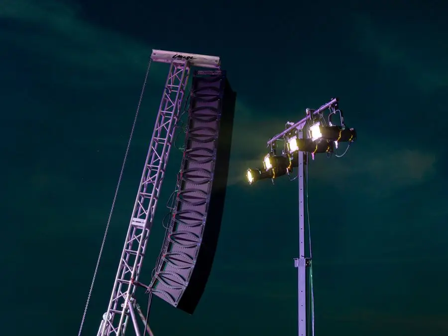 Palco de festival à noite com sistema de som e iluminação cênica
