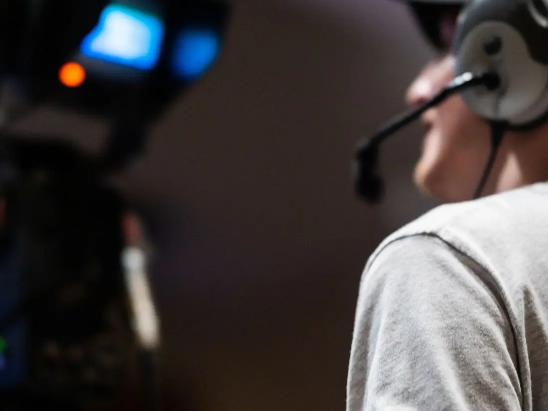 Cinegrafista com headset operando câmera de broadcast durante transmissão ao vivo